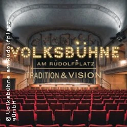 Blick in den Saal der Volksbühne mit rotem Gestühl und beleuchtetem Bühnen-Schriftzug