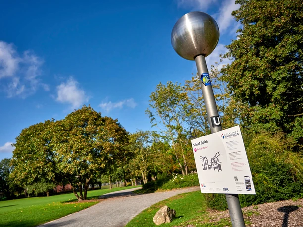 RUHRPERLE am Schloß Broich, Mülheim an der Ruhr Säule mit kugelförmigem Kopf und Infoschild (Bezeichnung: RUHRPERLE) bei sonnigem Wetter in einem Park mit großer Wiese und vielen Bäumen