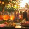 Gartenparty bei Sonnenuntergang mit Aperitifs und Freunden Menschen feiern im Garten bei Sonnenuntergang mit Aperitifs, Lichterketten und sommerlichen Snacks.