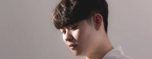 Weltklassik: Seunglee Yang Eine Person mit geschlossenen Augen und sanftem Ausdruck, in warmem Licht porträtiert.