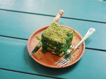 Grünkohlkuchen.jpg Ein Streuselkuchen mit Grünkohlbättern als Füllung auf einem braunem Teller