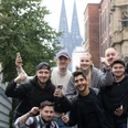Pokémon GO Community Eine Gruppe posiert glücklich mit erhobener Faust. Im Hintergrund ragt der Kölner Dom hervor. A group poses happily with a raised fist. Cologne Cathedral looms in the background.