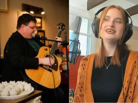 Wochenmarkt mit Musik 4000x3000.png Zwei Personen mit Mikrofonen, ein Mann spielt akustische Gitarre, und eine Frau trägt Kopfhörer und ein orangefarbenes Strickjäckchen