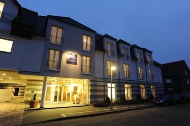 Beleuchtete Fassade des Hotels Appelbaum bei Nacht mit Eingang, Balkonen und ruhiger Straße.