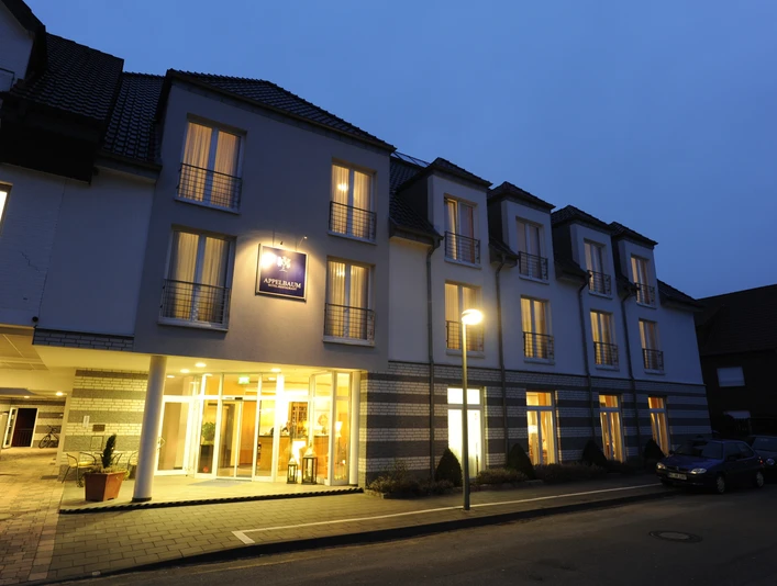 Beleuchtete Fassade des Hotels Appelbaum bei Nacht mit Eingang, Balkonen und ruhiger Straße.