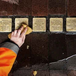 Stolpersteine Detlef Güthenke Hand reinigt Stolpersteine mit Namen deportierter NS-Opfer Bürger im Gehweg