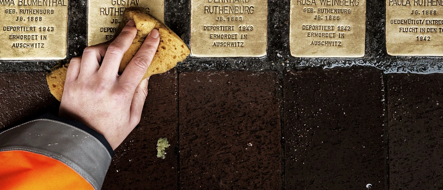 Stolpersteine Detlef Güthenke Hand reinigt Stolpersteine mit Namen deportierter NS-Opfer Bürger im Gehweg