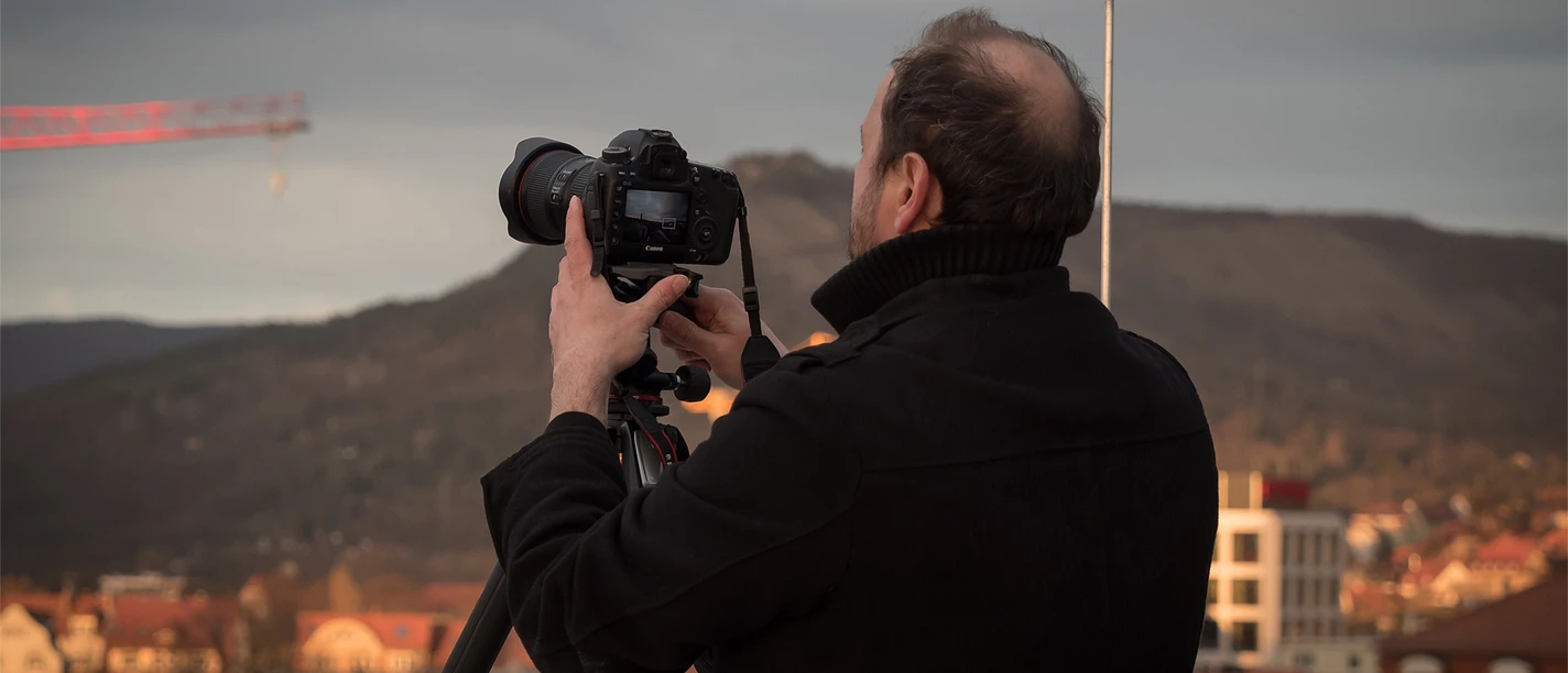 Ein Mann steht hinter einer Kamera und fotografiert eine Stadt