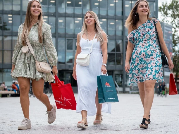 Drei junge Frauen schlendern mit Einkaufstüten über den Marktplatz in Achern
