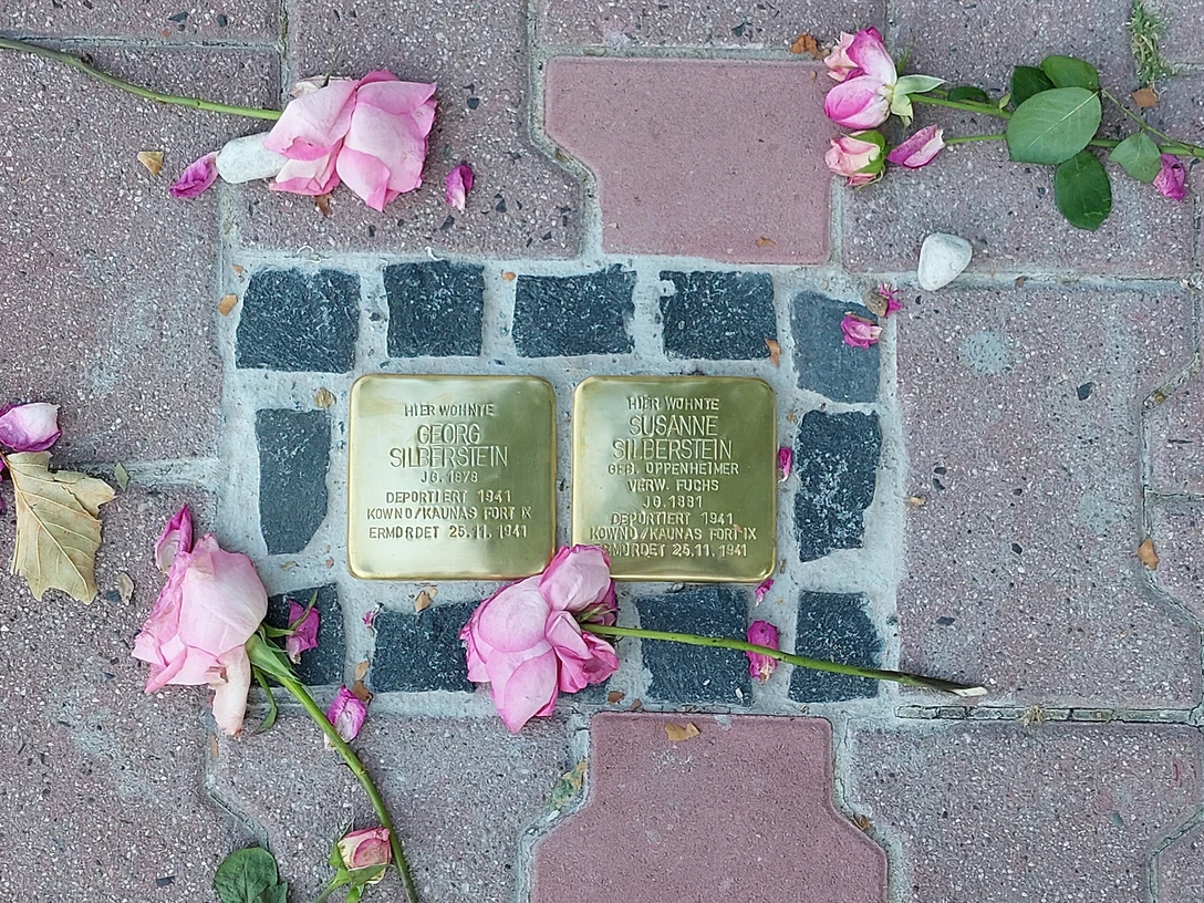 Stolpersteine Zwei Stolpersteine mit Rosen auf PflastersteinenTwo Stolpersteine with roses on pavement