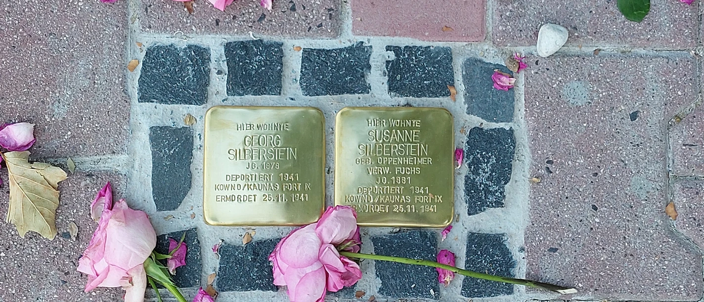 Stolpersteine Two Stolpersteine with roses on pavement