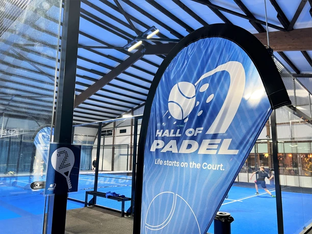 Hall of Padel Innenansicht einer modernen Padelhalle mit blauem Spielfeld und spielenden Personen im Hintergrund