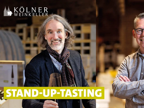 Stand-up-tasting im Weinkeller Zwei Männer lächeln in die Kamera. Im Hintergrund erkennt man einen Weinkeller.