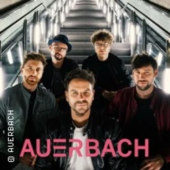 Fünf Personen vor beleuchteter Rolltreppe, mit Schriftzug AUERBACH im unteren Bildbereich