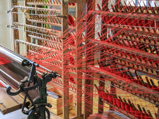 Einblicke in die Tuchherstellung im Tuchmacher Museum in Bramsche Detailaufnahme aus dem Tuchmachermuseum Bramsche, mit Webstuhl, Garnen und historischer Technik der Textilproduktion.