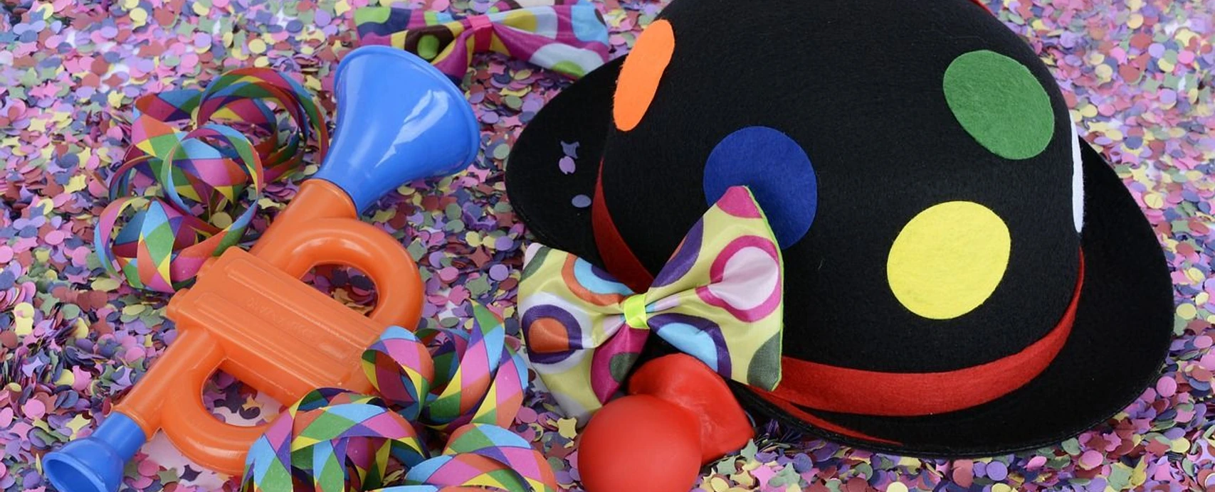 Fasching Bunte Faschingsdekoration mit Konfetti, Clownhut, Fliege, Luftschlangen und Spieltrompete