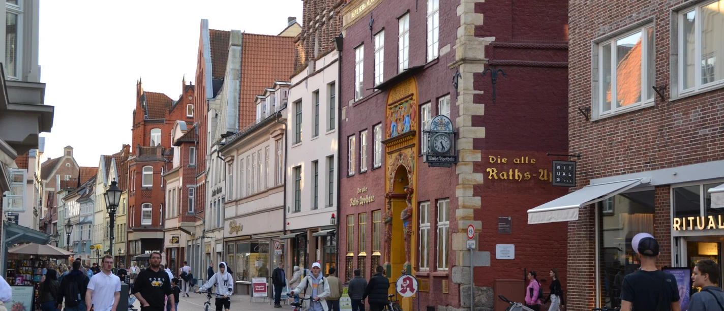 191459585_Bäckerstraße_CC BY-SA_©Lüneburg Marketing GmbHMerle-Marie Matthießen.jpg Passanten in der Lüneburger Fußgängerzone vor der historischen Alten Raths-Apotheke.