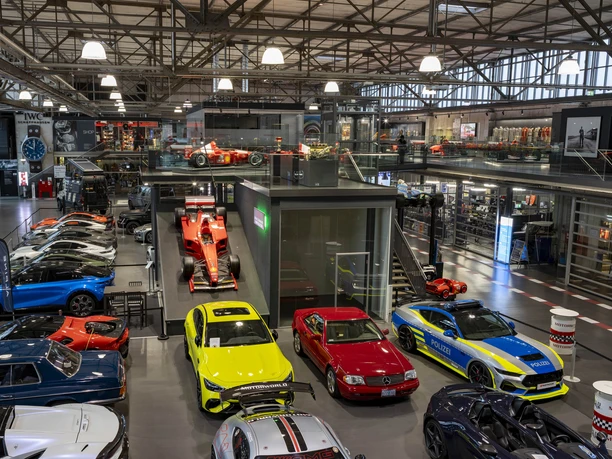 MOTORWORLD Köln Rheinland Große Halle mit Sportwagen, Oldtimern und roten Formelwagen auf zwei Ebenen der Motorworld