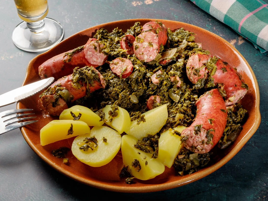 Grünkohl Grünkohl mit Mettenden und Salzkartoffeln auf brauner Platte, servierfertig