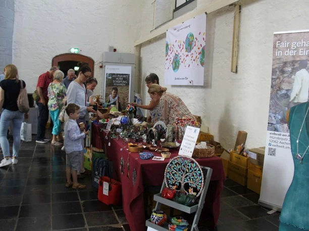 In einer Kirche sind verschiedene Messestände aufgebaut, die fairtrade Produkte präsentieren.