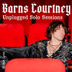 Musiker sitzt entspannt in roten Kinosesseln, umgeben von Schriftzug zu Unplugged Sessions