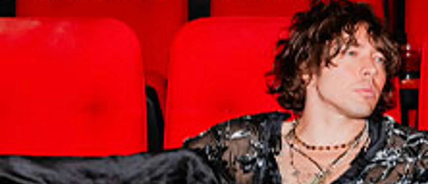 Musiker sitzt entspannt in roten Kinosesseln, umgeben von Schriftzug zu Unplugged Sessions