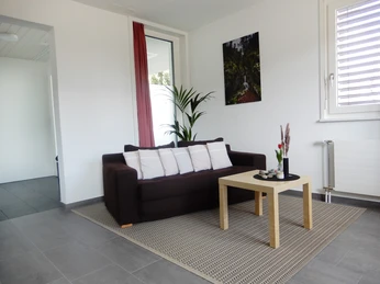 Ferienwohnung Roos Ohmstal Modernes Wohnzimmer der Ferienwohnung Roos Ohmstal mit Sofa Couchtisch und grossem Fenster