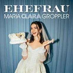 Frau im Brautkleid lächelnd vor blauem Vorhang, hält angeschnittene Hochzeitstorte