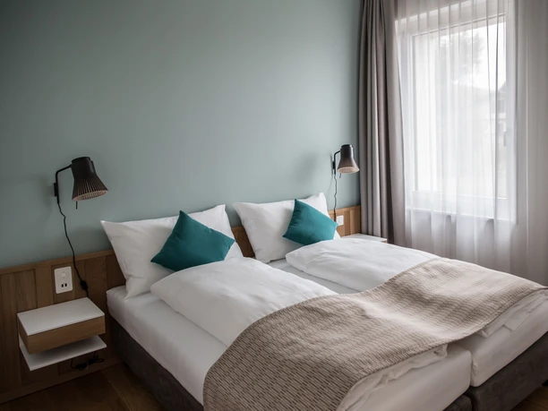 Aparthotel Luzern West Alberswil Helles Schlafzimmer im Aparthotel Luzern West mit zwei Betten, stilvollen Kissen und grossem Fenster mit Vorhängen