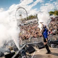 Rainbow Festival Bühnenaufnahme mit singender Person, Rauch und großer Festivalmenge vor RiesenradStage shot with singing person, smoke and large festival crowd in front of Ferris wheel
