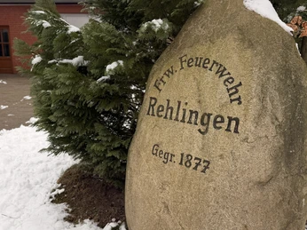 Stein FFW Rehlingen Großer Gedenkstein der Freiwilligen Feuerwehr Rehlingen mit Inschrift im winterlich verschneiten Hof.