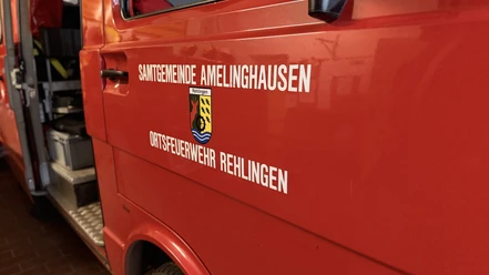 Einsatzfahrzeug Rehlingen Rotes Einsatzfahrzeug der Ortsfeuerwehr Rehlingen mit Wappen und geöffneter Tür in der Fahrzeughalle.
