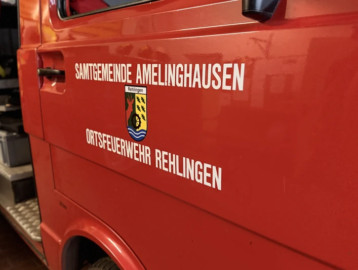 Einsatzfahrzeug Rehlingen Rotes Einsatzfahrzeug der Ortsfeuerwehr Rehlingen mit Wappen und geöffneter Tür in der Fahrzeughalle.
