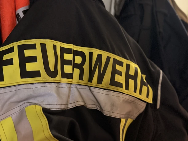 IMG_0794.jpg Rückansicht einer schwarzen Feuerwehrjacke mit gelbem Schriftzug FEUERWEHR.
