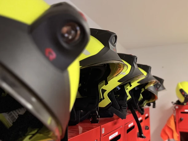 IMG_0774 2.jpg Gelbe Feuerwehrhelme hängen ordentlich aufgereiht an roten Spinden in der Feuerwache.