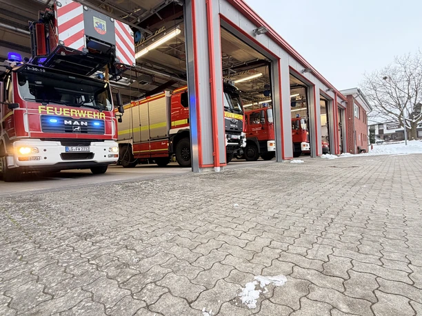 IMG_0781.jpg Feuerwehrhaus mit mehreren Einsatzfahrzeugen in roten Hallen, winterlicher Vorplatz mit Schnee.