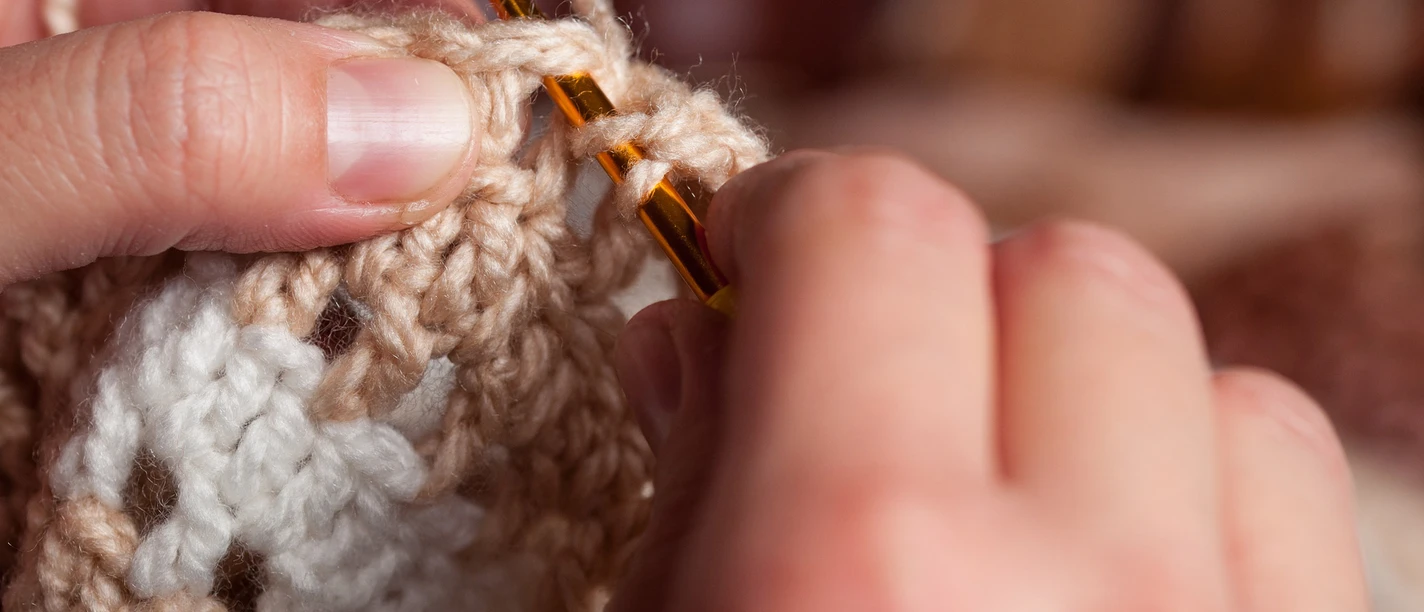 AdobeStock_296178935-2560x1707.jpg Zwei Hände mit Häkel-Nadel