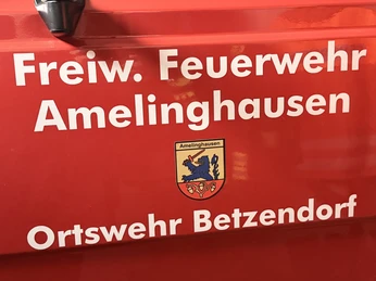IMG_0800.jpg Rote Fahrzeugseite mit weißer Aufschrift „Freiw. Feuerwehr Amelinghausen Ortswehr Betzendorf“ und Wappen.