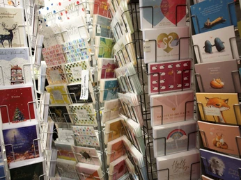 2026-01-Dodt-Schreibwaren-glueckwunschkarten.jpg Mehrere Regale voller bunter Glückwunschkarten mit Tiermotiven, Schriftzügen und festlichen Designs.