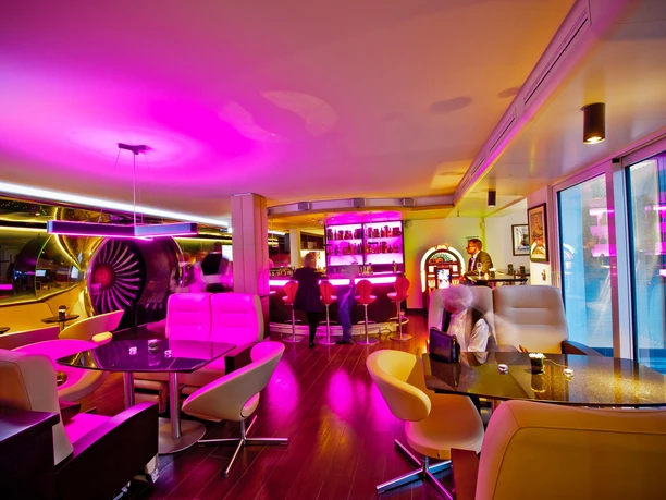 The Aircraft at Burghof - Lounge Stilvolle Lounge im Luftfahrt-Design mit pinkfarbener Neonbeleuchtung