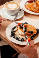 Kaffee mit Herz im Schaum, Pancakes mit Blaubeeren, Erdbeeren und Soße im Café Lieblingsplatz