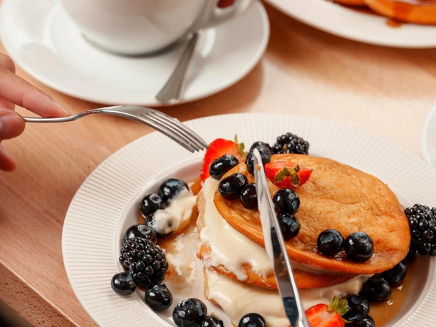 2025-09-01-lieblingsplatz-093_(c) Andreas Behr_WEB.jpg Kaffee mit Herz im Schaum, Pancakes mit Blaubeeren, Erdbeeren und Soße im Café Lieblingsplatz