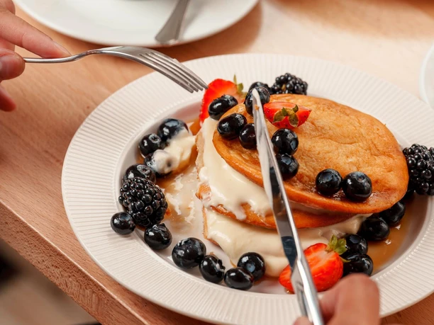 Kaffee mit Herz im Schaum, Pancakes mit Blaubeeren, Erdbeeren und Soße im Café Lieblingsplatz