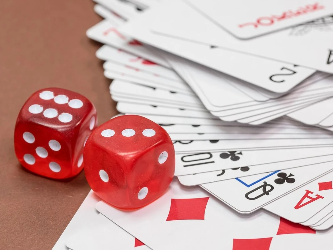 Spieleabend Zwei rote Würfel liegen auf Spielkarten und wecken Lust auf gesellige Spielrunden.