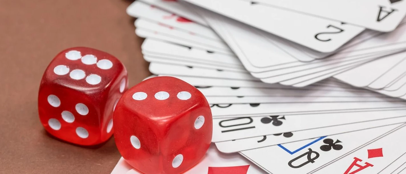 Spieleabend Zwei rote Würfel liegen auf Spielkarten und wecken Lust auf gesellige Spielrunden.