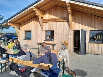 Die Atzmannhütte liegt am Wisper Trail Dickschieder Wildwechsel Außenbereich der Atzmannhütte. Wanderer haben sich für eine Pause an Bierbänke gesetzt.