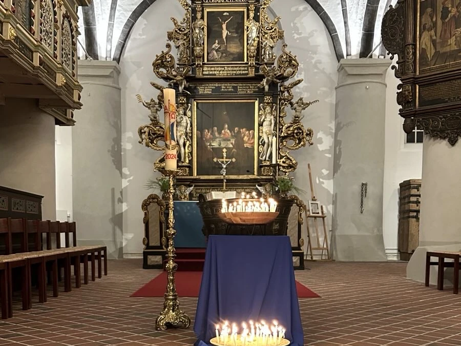 Taizé Gottesdienst Kerzenlicht auf blauem Tuch vor barockem Altar in der St. Severi-Kirche während eines Taizé-Gebets.
