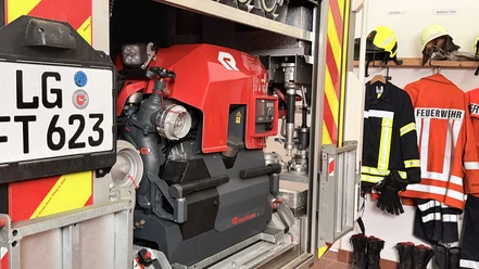 IMG_0798.jpg Nahaufnahme einer tragbaren Feuerlöschpumpe in der Halterung eines Einsatzfahrzeugs mit Ausrüstung.