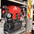 IMG_0798.jpg Nahaufnahme einer tragbaren Feuerlöschpumpe in der Halterung eines Einsatzfahrzeugs mit Ausrüstung.