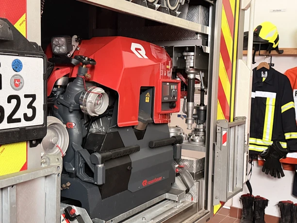 IMG_0798.jpg Nahaufnahme einer tragbaren Feuerlöschpumpe in der Halterung eines Einsatzfahrzeugs mit Ausrüstung.